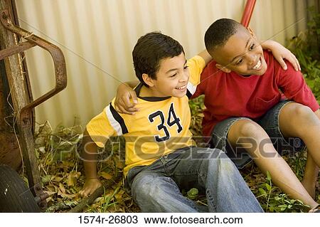 Stock Image - Friends sitting with arms around by push cart. Fotosearch