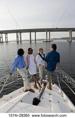 Friends standing at bow of a boat View Large Photo Image Stock Photography - Friends standing at bow of a boat. Fotosearch