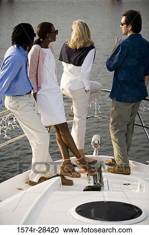 Friends standing together and conversing at bow of a boat View Large Photo Image Stock Image - Friends standing together and conversing at bow of a boat. Fotosearch