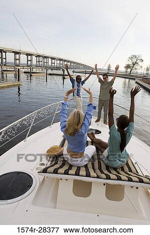 Friends with arms raised on the deck of a boat View Large Photo Image Stock Photo - Friends with arms raised on the deck of a boat. Fotosearch
