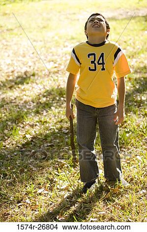 Frustrated boy standing with a stick on the grass View Large Photo Image Picture - Frustrated boy standing with a stick on the grass. Fotosearch