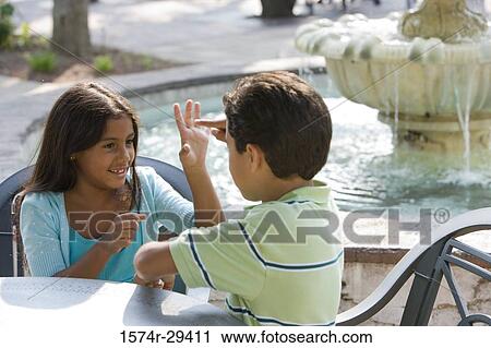 Girl and boy sitting together by table and playing View Large Photo Image Stock Image - Girl and boy sitting together by table and playing. Fotosearch