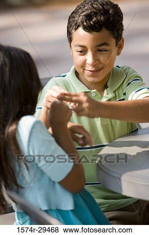 Girl and boy sitting together by table and playing View Large Photo Image Stock Photo - Girl and boy sitting together by table and playing. Fotosearch