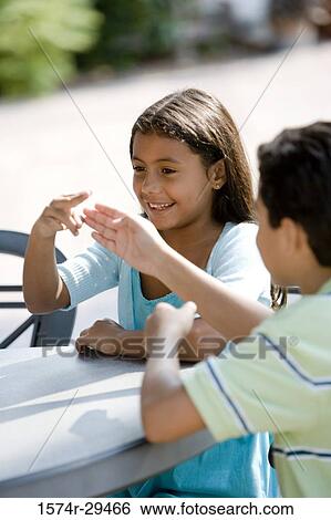Stock Photograph - Girl and boy sitting together by table and playing. Fotosearch