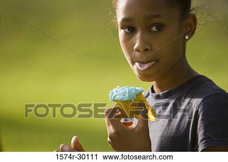 Girl holding a cupcake at park View Large Photo Image Stock Image - Girl holding a cupcake at park. Fotosearch
