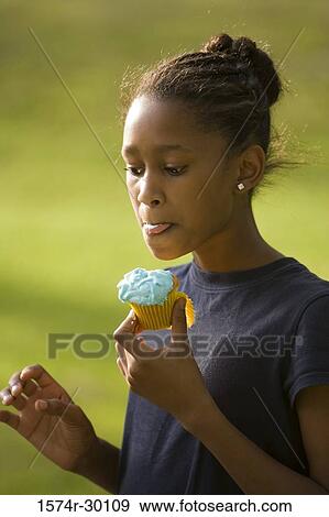 Stock Photo - Girl holding a cupcake at park. Fotosearch