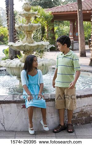 Girl sitting by water fountain while boy standing View Large Photo Image Stock Photography - Girl sitting by water fountain while boy standing. Fotosearch