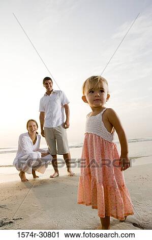 Girl standing on the beach with parents in the background View Large Photo Image Stock Image - Girl standing on the beach with parents in the background. Fotosearch