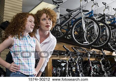 Girl with her mother in a bicycle shop View Large Photo Image Stock Image - Girl with her mother in a bicycle shop. Fotosearch