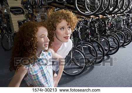 Girl with her mother in a bicycle shop View Large Photo Image Stock Image - Girl with her mother in a bicycle shop. Fotosearch