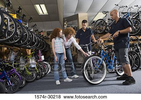 Stock Photo - Girl with her mother looking at a bicycle in a bicycle shop. Fotosearch