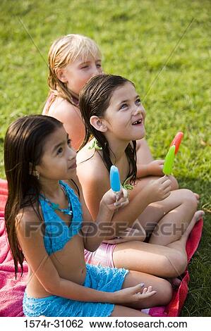 Girls sitting on towel with flavored ice View Large Photo Image Stock Image - Girls sitting on towel with flavored ice. Fotosearch