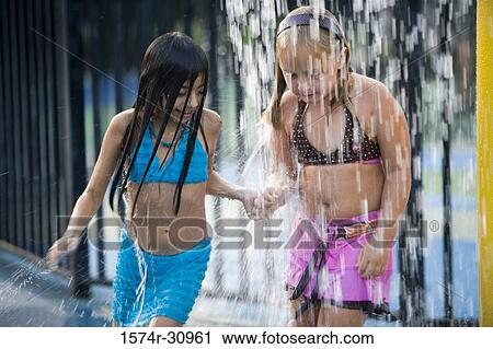 Stock Image - Girls standing together under a shower. Fotosearch