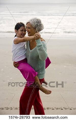 Grandmother carrying her granddaughter at the beach View Large Photo Image Stock Image - Grandmother carrying her granddaughter at the beach. Fotosearch