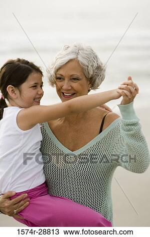 Stock Image - Grandmother carrying her granddaughter at the beach. Fotosearch