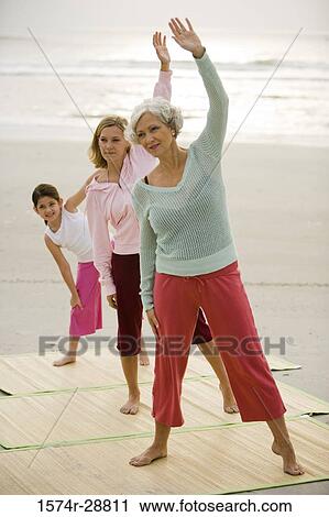 Stock Image - Grandmother exercising with her daughter and granddaughter at the beach. Fotosearch