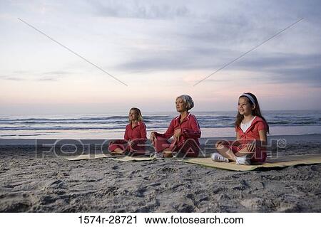 Stock Image - Grandmother with her daughter and granddaughter exercising at the beach. Fotosearch