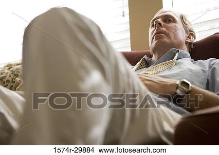 Low angle view of a businessman relaxing on a sofa View Large Photo Image Picture - Low angle view of a businessman relaxing on a sofa. Fotosearch