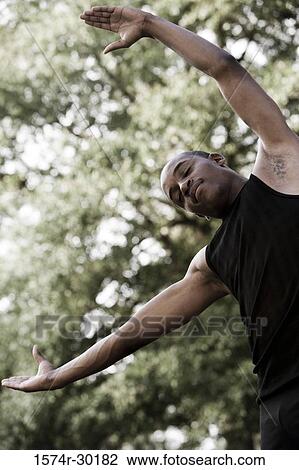 Low angle view of a young man standing under tree with eyes closed and his arms out View Large Photo Image Stock Image - Low angle view of a young man standing under tree with eyes closed and his arms out. Fotosearch