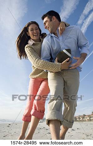 Low angle view of cheerful couple playing on a beach View Large Photo Image Stock Photography - Low angle view of cheerful couple playing on a beach. Fotosearch