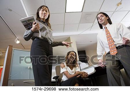 Stock Photo - Low angle view of colleagues standing together in an office. Fotosearch