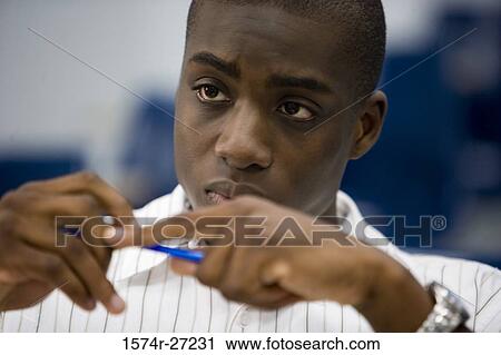 Male student holding a pen in the classroom View Large Photo Image Stock Image - Male student holding a pen in the classroom. Fotosearch