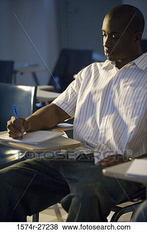 Male student writing on book in the classroom View Large Photo Image Stock Photo - Male student writing on book in the classroom. Fotosearch