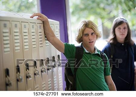 Male students standing by locker in corridor View Large Photo Image Stock Image - Male students standing by locker in corridor. Fotosearch