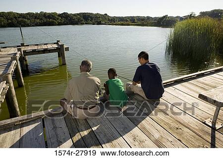 Man fishing with his son and friend on jetty View Large Photo Image Stock Photo - Man fishing with his son and friend on jetty. Fotosearch