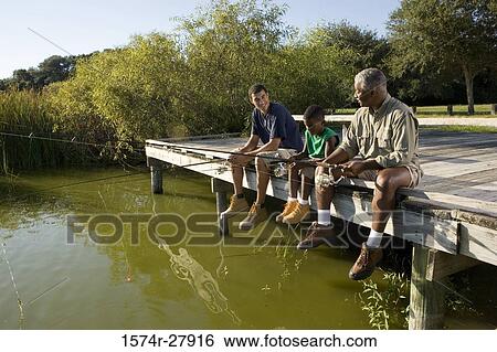 Stock Photograph - Man fishing with his son and friend on jetty. Fotosearch