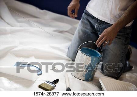 Man kneeling by paint can and paintbrush on drop cloth View Large Photo Image Stock Photo - Man kneeling by paint can and paintbrush on drop cloth. Fotosearch