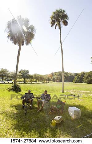 Man relaxing with his friend and son on chair at forest View Large Photo Image Picture - Man relaxing with his friend and son on chair at forest. Fotosearch