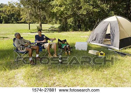 Man sitting with his friend and son on chair by tent at forest View Large Photo Image Stock Image - Man sitting with his friend and son on chair by tent at forest. Fotosearch