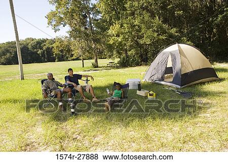 Man with his son and friend conversing by tent at forest View Large Photo Image Stock Photo - Man with his son and friend conversing by tent at forest. Fotosearch