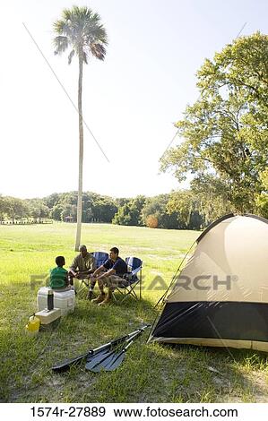 Man with his son and friend conversing by tent at forest View Large Photo Image Stock Photo - Man with his son and friend conversing by tent at forest. Fotosearch