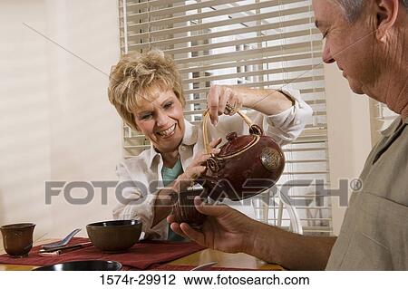 Mature couple by breakfast table pouring tea into a cup View Large Photo Image Stock Image - Mature couple by breakfast table pouring tea into a cup. Fotosearch