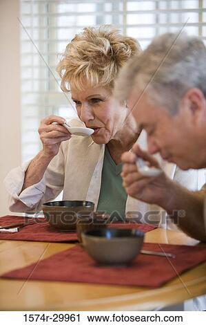 Mature couple having food at a dining table View Large Photo Image Stock Image - Mature couple having food at a dining table. Fotosearch