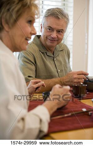 Mature couple having food at a dining table View Large Photo Image Stock Photo - Mature couple having food at a dining table. Fotosearch