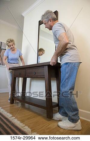 Mature couple holding a table View Large Photo Image Picture - Mature couple holding a table. Fotosearch