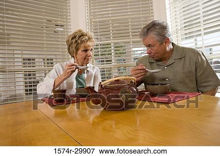 Mature couple sitting at breakfast table and having soup View Large Photo Image Stock Photo - Mature couple sitting at breakfast table and having soup. Fotosearch