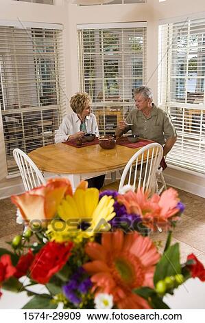 Stock Photo - Mature couple sitting at breakfast table and having soup. Fotosearch