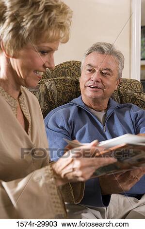 Stock Image - Mature couple sitting together and holding a book. Fotosearch