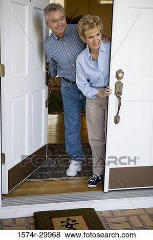 Stock Photo - Mature couple standing together by a door and smiling. Fotosearch