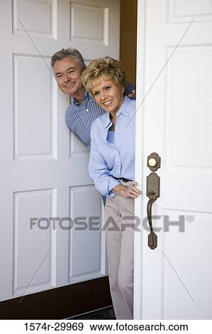 Mature couple standing together by a door and smiling View Large Photo Image Stock Photo - Mature couple standing together by a door and smiling. Fotosearch