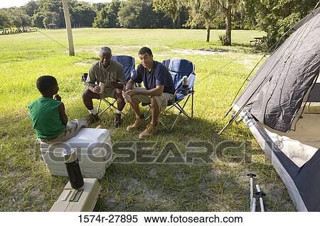 Mature man and his friend sitting with a boy by tent at forest View Large Photo Image Stock Photography - Mature man and his friend sitting with a boy by tent at forest. Fotosearch