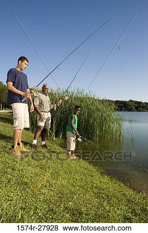 Stock Photo - Mature man fishing with his son and friend by lake. Fotosearch