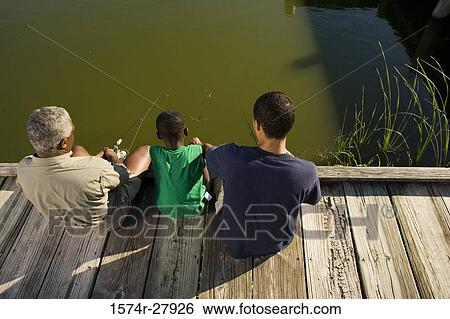 Stock Photograph - Mature man fishing with his son and friend on jetty. Fotosearch