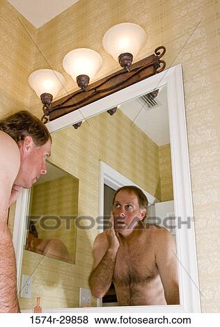 Mature man looking at his face in the bathroom mirror View Large Photo Image Stock Photo - Mature man looking at his face in the bathroom mirror. Fotosearch