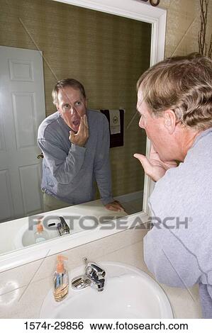 Mature man looking at his face in the bathroom mirror View Large Photo Image Stock Photograph - Mature man looking at his face in the bathroom mirror. Fotosearch