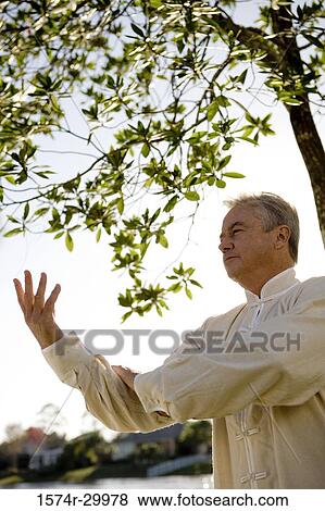 Stock Photo - Mature man performing martial arts in the park. Fotosearch